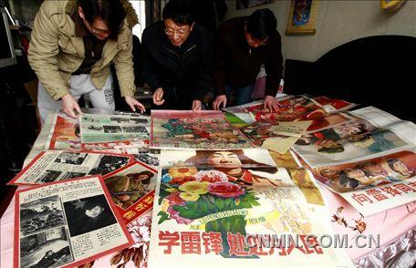 3月1日，房冠龍（中）在家中整理關(guān)于雷鋒的宣傳海報。