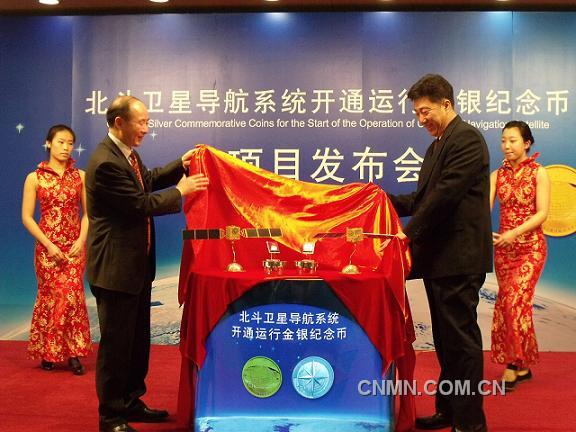 中國金幣總公司董事長徐聯初與總參測繪導航局衛星導航定位工程辦公室主任楊寶峰共同為北斗衛星導航系統開通運行金銀紀念幣揭幕