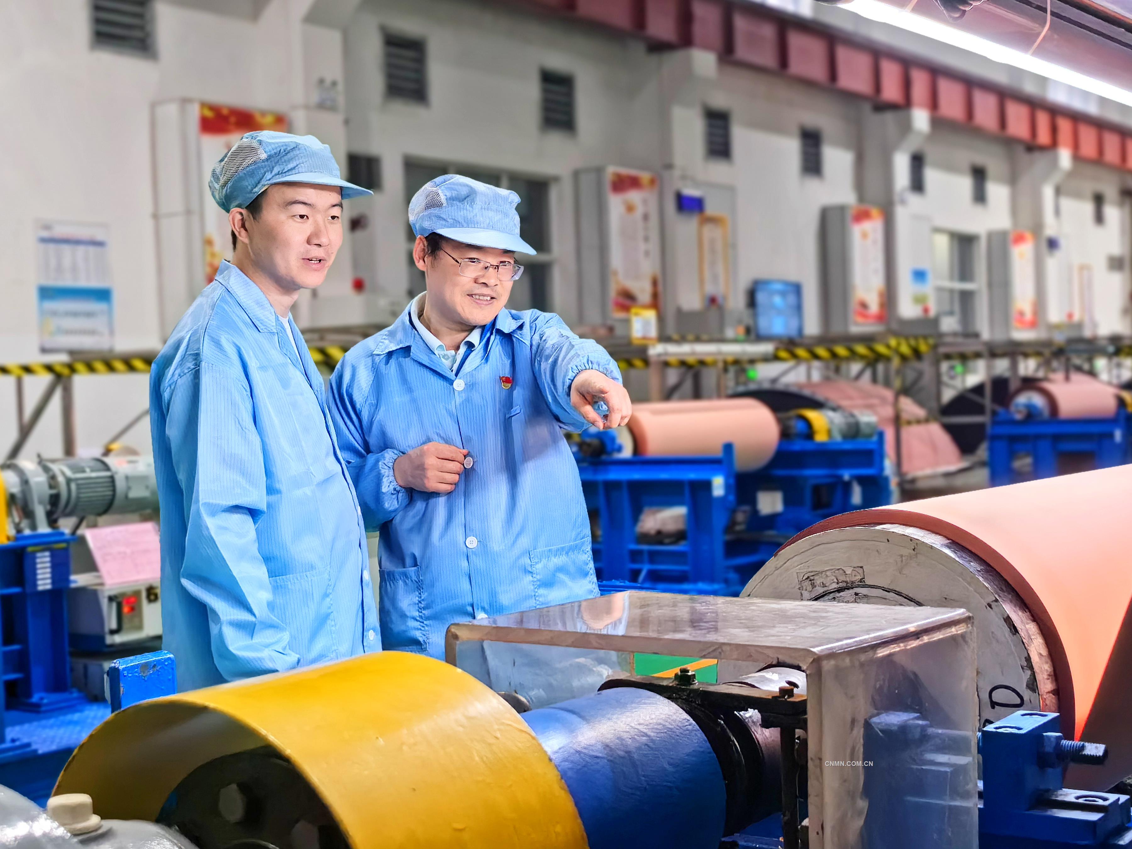 李大雙(右)和徒弟黃超在生產現場檢查銅箔表面外觀